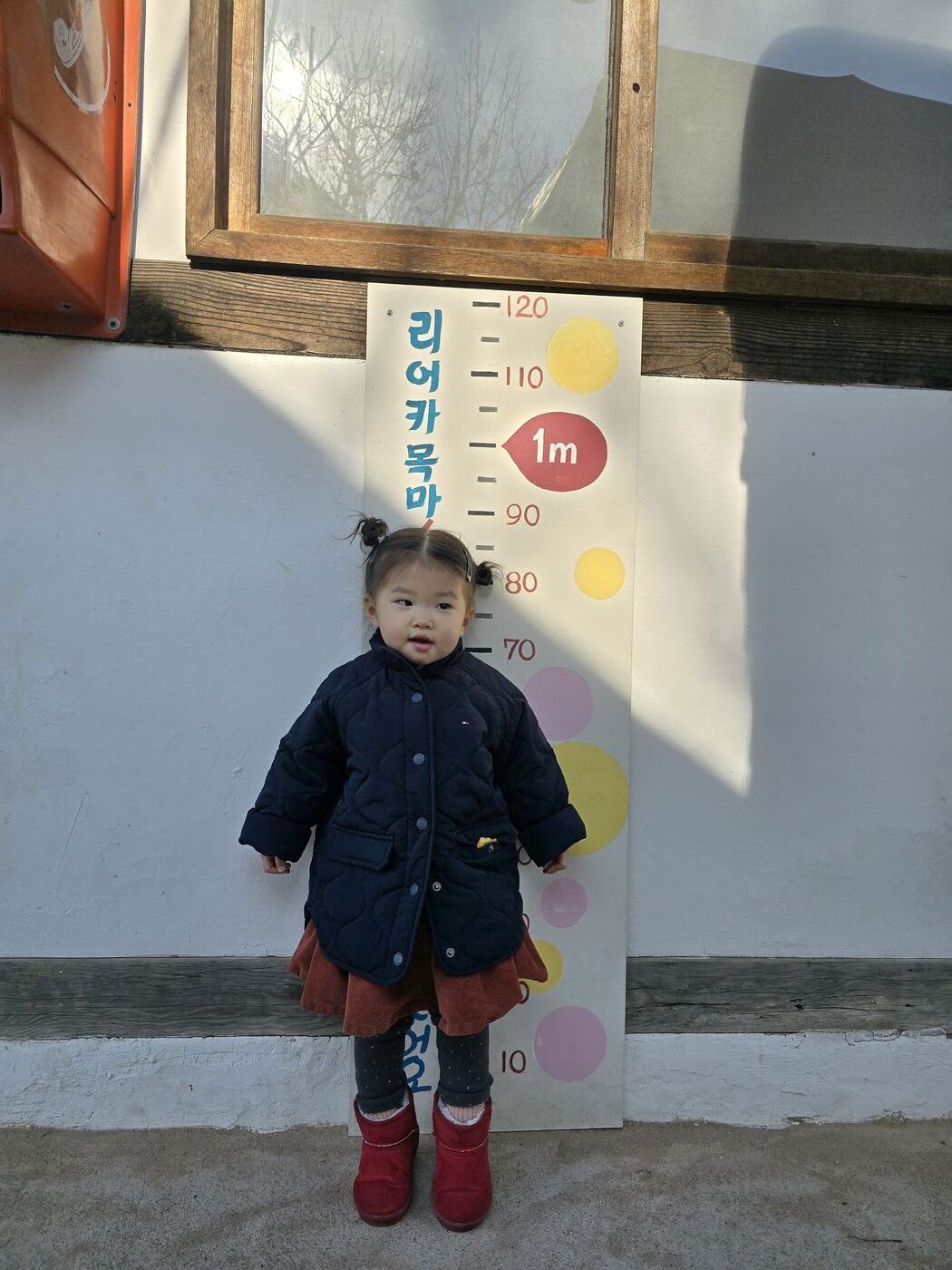 toddler at height measurement board at children's museum entrance