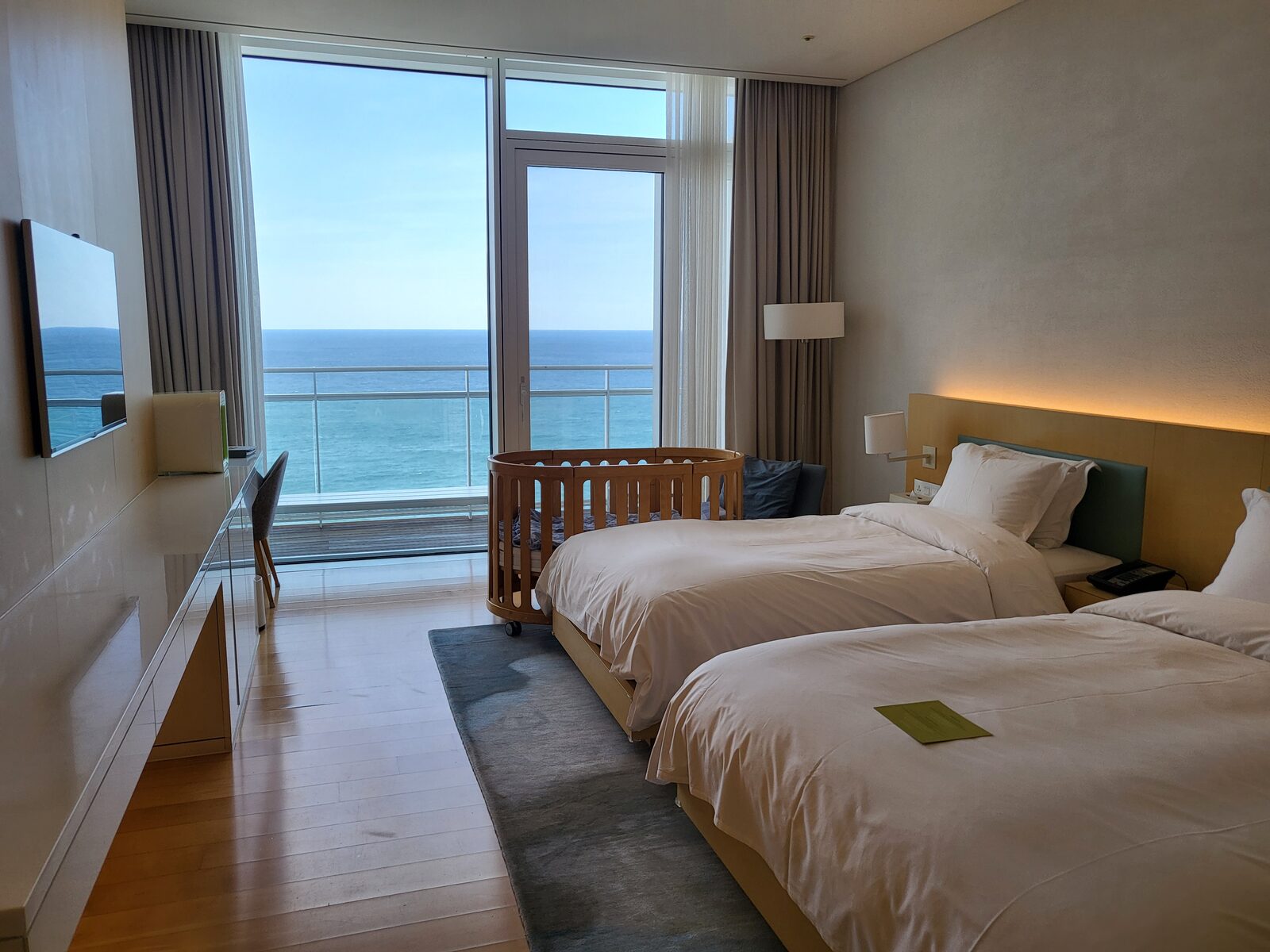 Ocean view room with twin beds and a round baby crib at SEAMARQ Hotel Gangneung