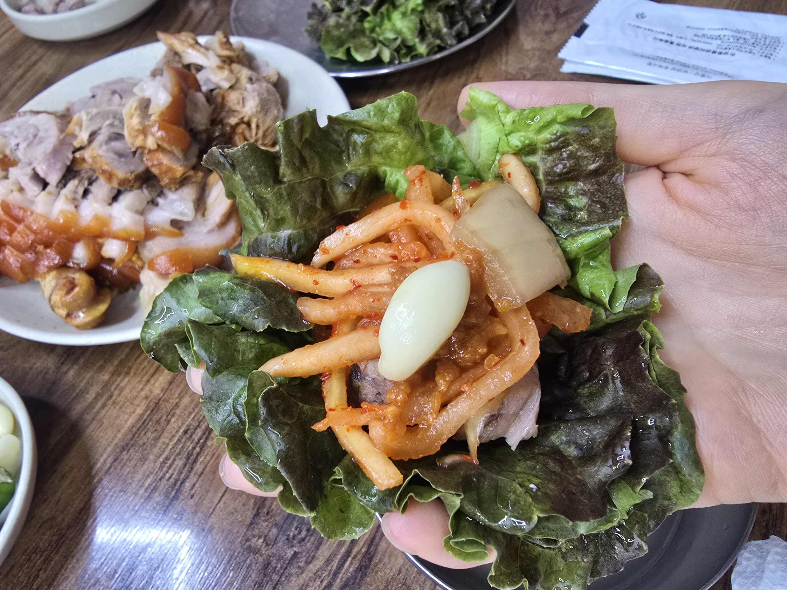 How to eat Korean jokbal wrapped in lettuce with garlic and kimchi