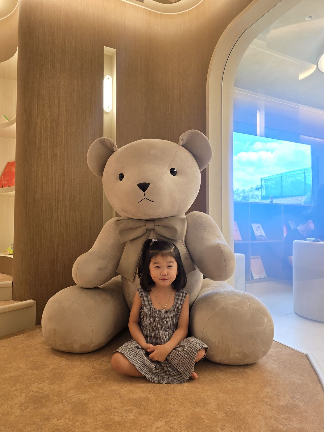 Child sitting in a giant teddy bear chair at the Kids Lounge